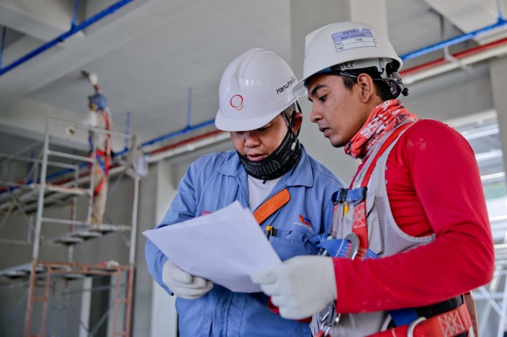 Workers in hard hats going over some papers