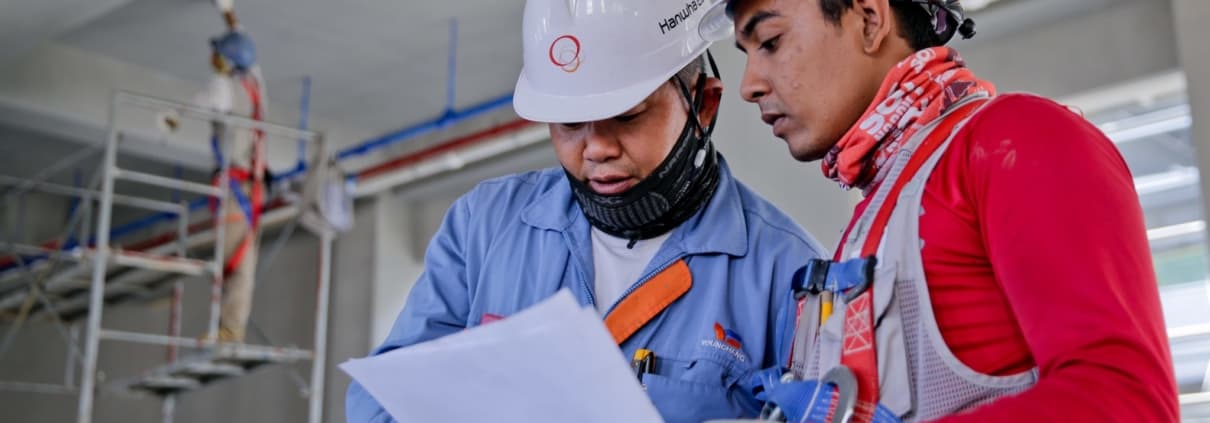Workers in hard hats going over some papers