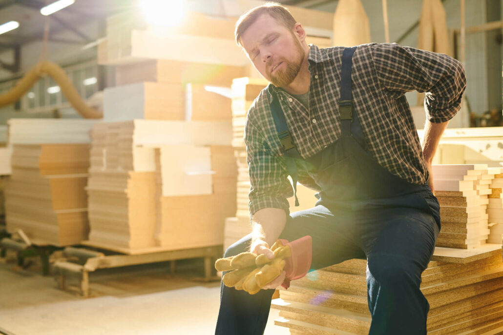 Male factory worker sitting with hurt back