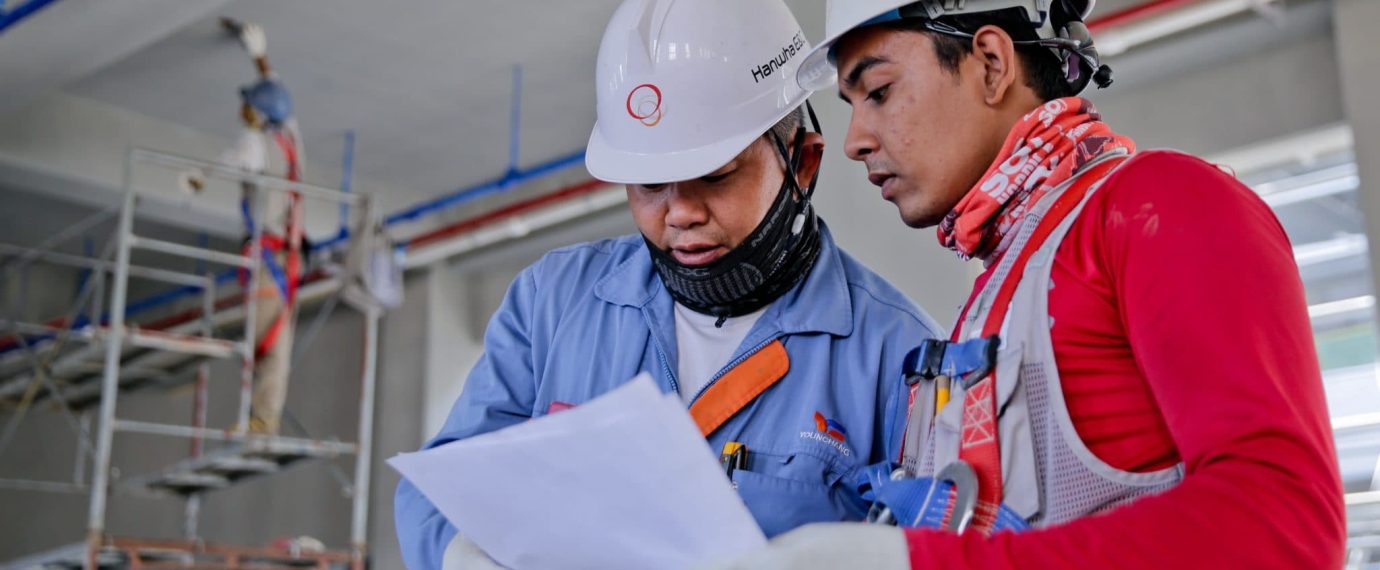 Workers in hard hats going over some papers