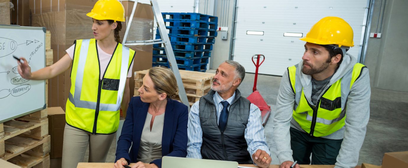 Warehouse workers and managers discussing plan on whiteboard in warehouse