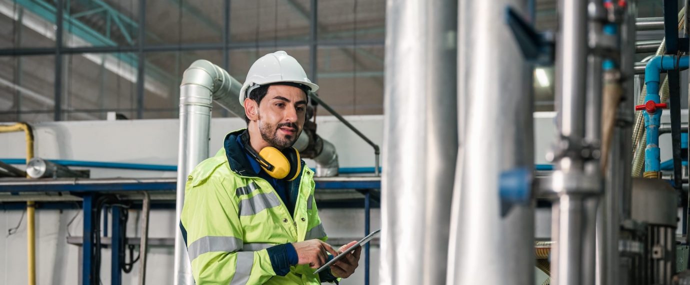 Man in safety vest with tablet in manufacturing plant