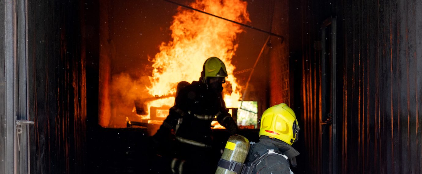 Two firefighters of fireman try to extinguish the fire in container during the practice of their job.