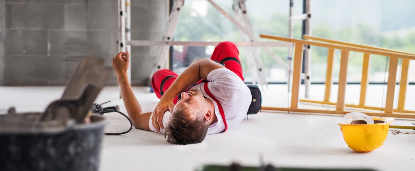 Accident of a male worker at the construction site. An injured man on the floor.